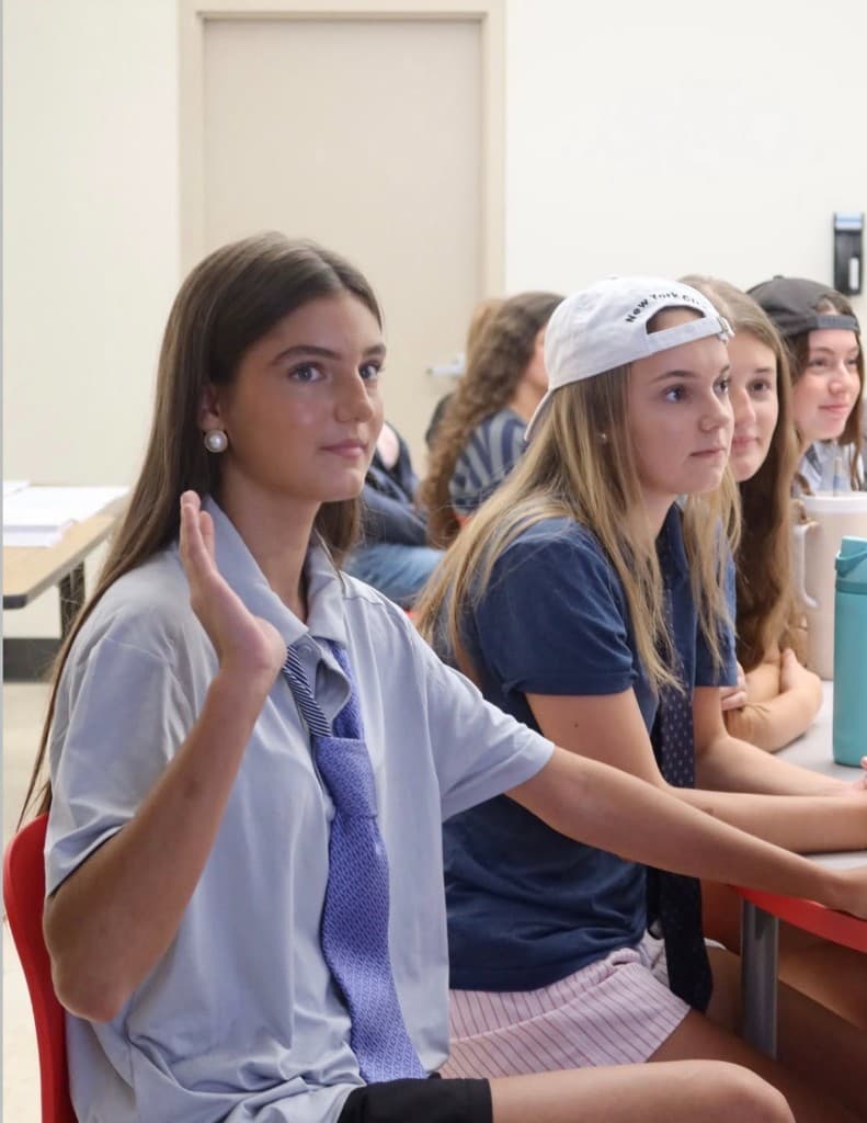 Student raising her hand during a HER classroom discussion