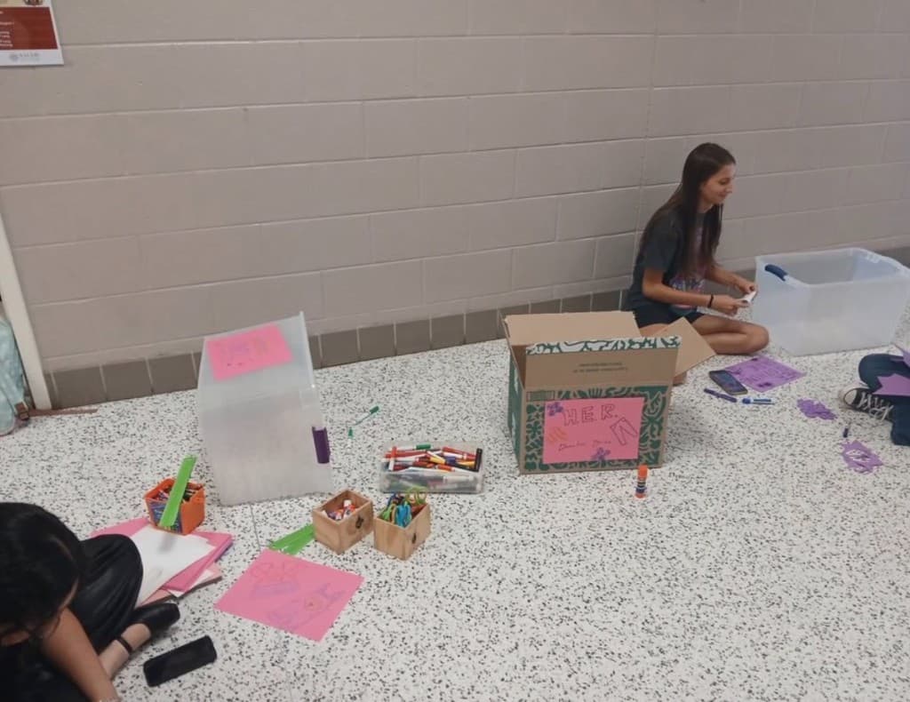 Students assembling materials for a H.E.R. donation drive