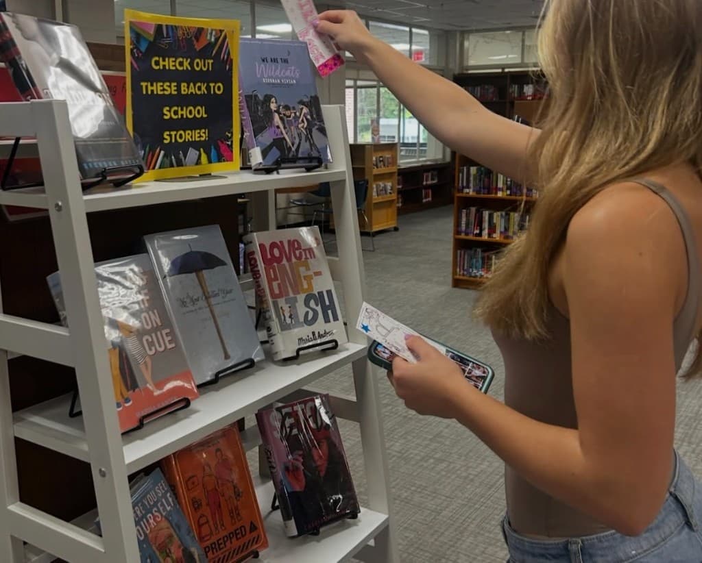 Student placing HER bookmarks in a school library display