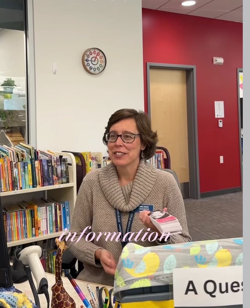 Library Director Bree Drapa holding History by HER materials